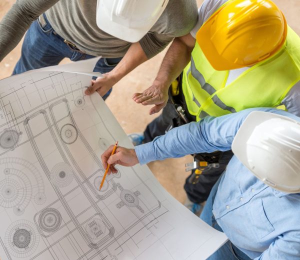 civil-engineers-looking-at-blueprints-473683922-5c14287446e0fb00014ad74b-scaled
